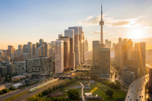 Aerial view of a city skyline during sunset, featuring tall skyscrapers, including a tower, with sun rays creating a warm glow over the buildings and streets.